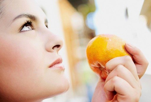 Close_up of a young woman holding an orange