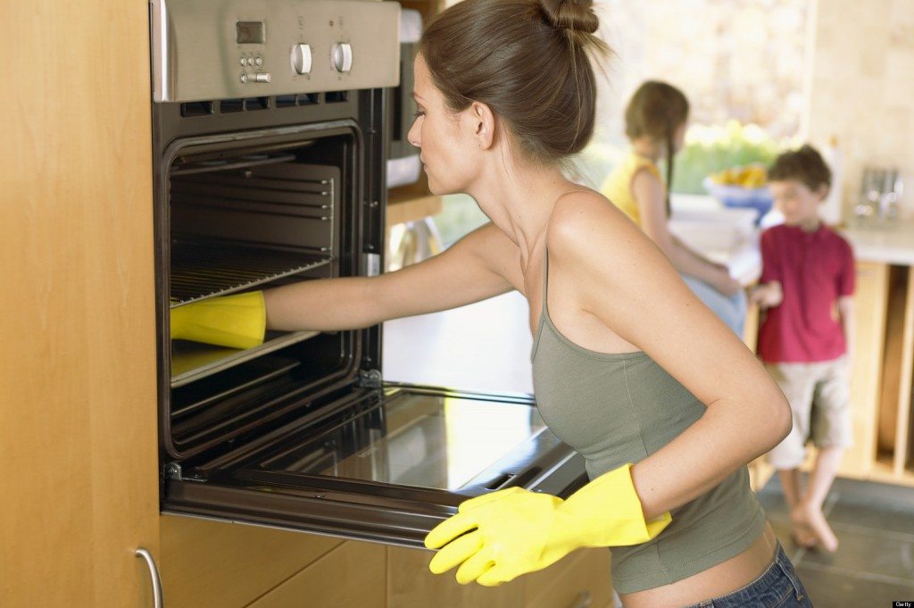 Woman cleaning oven --- Image by © Lou Cypher/Corbis